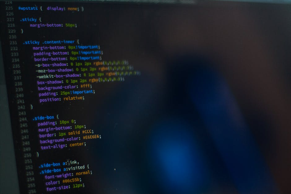 A close-up view of a laptop screen displaying lines of programming code, with the code editor open to a section involving variable checks and validation functions. The keyboard, illuminated in a soft 