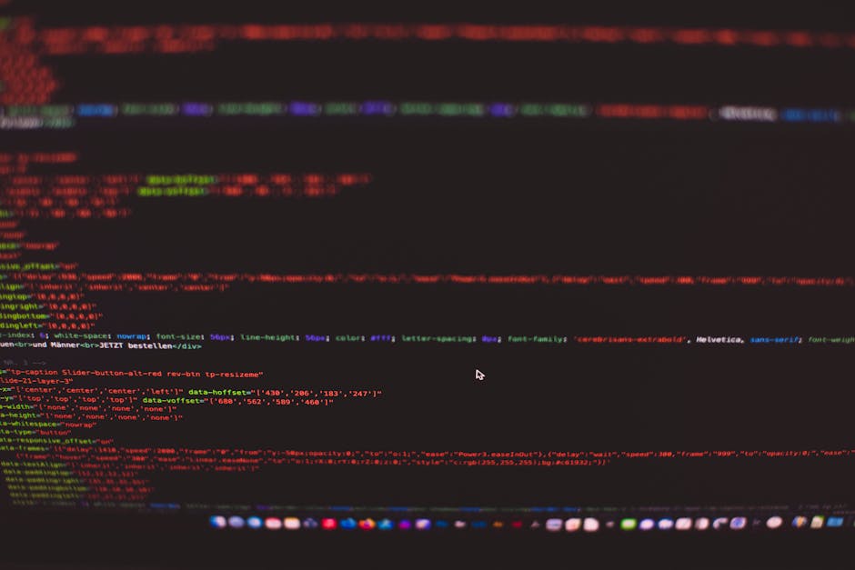 A close-up of a person's hands typing on a laptop keyboard, with the screen displaying lines of programming code in a dark-themed coding environment. The laptop is placed on a black smooth surface, an